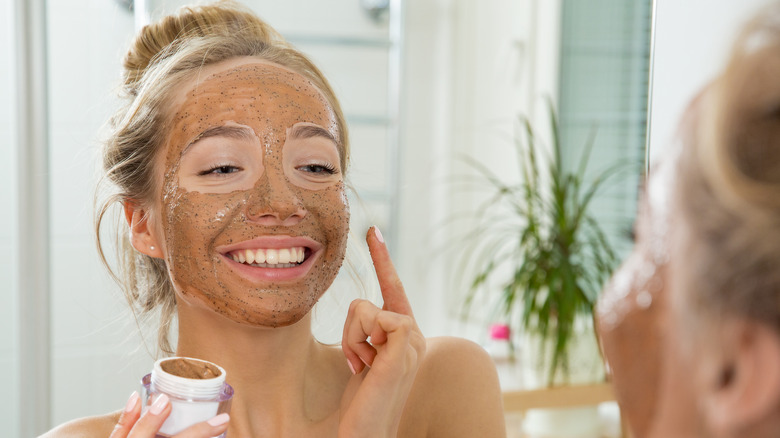 Woman smiling with an exfoliating face mask on