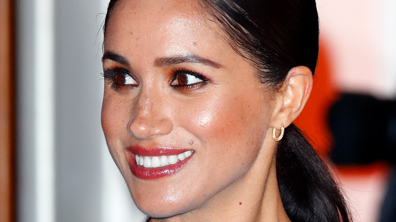 Meghan Markle smiling in a blue dress