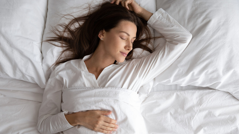 Woman sleeping on her back with her arm above her head