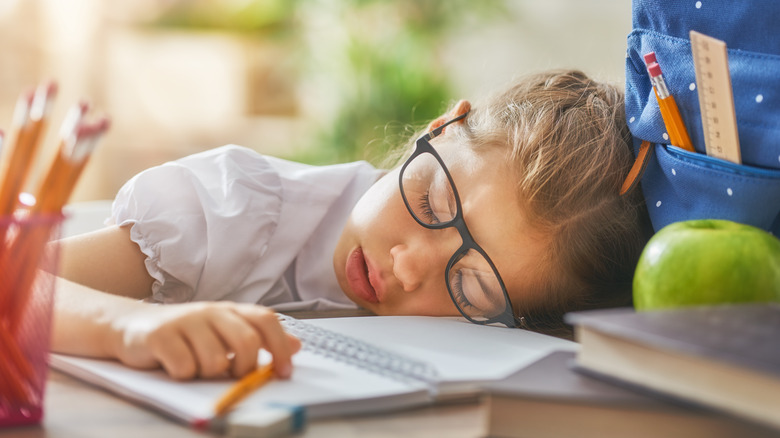 Little girl sleeping with schoolwork