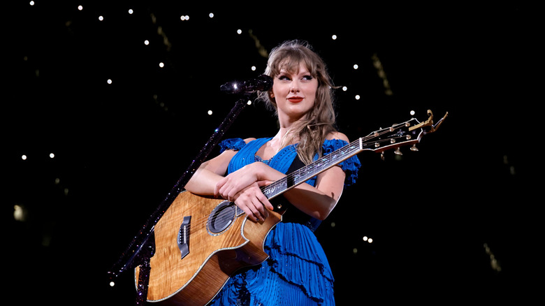 Taylor Swift plays a guitar onstage