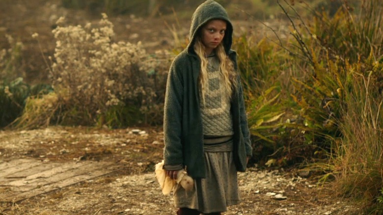 Amiah MIller in a hooded coat standing in a field in "War for the Planet of the Apes"