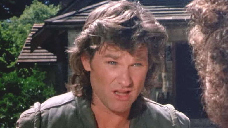 Kurt Russell with long hair standing outside in "Overboard"