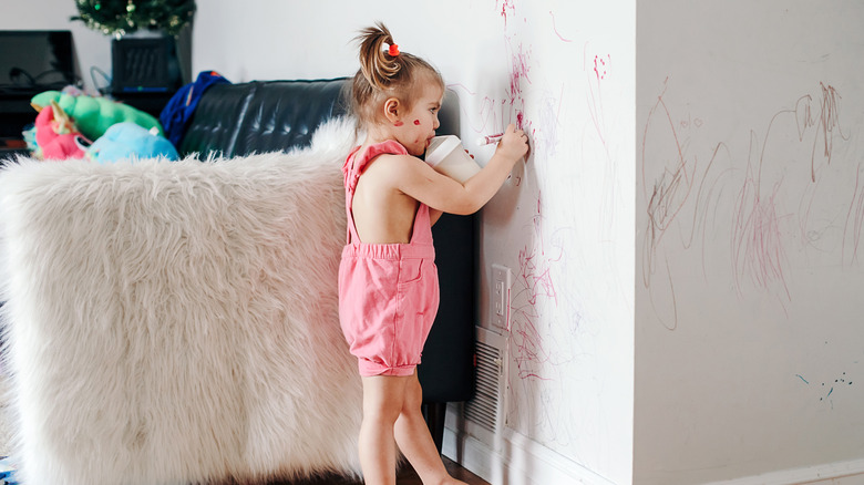 little girl drawing on wall 