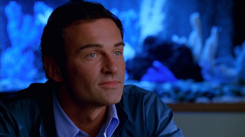Julian McMahon as Christian in Nip/Tuck, in front of a glowing blue fishtank