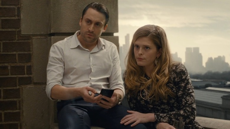 Kieran Culkin as Roman Roy and Molly Griggs as Grace Roy on Succession, sitting on a balcony ledge