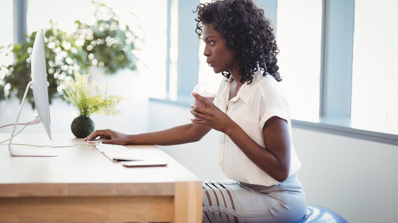 A woman sits on a stability ball at her desk