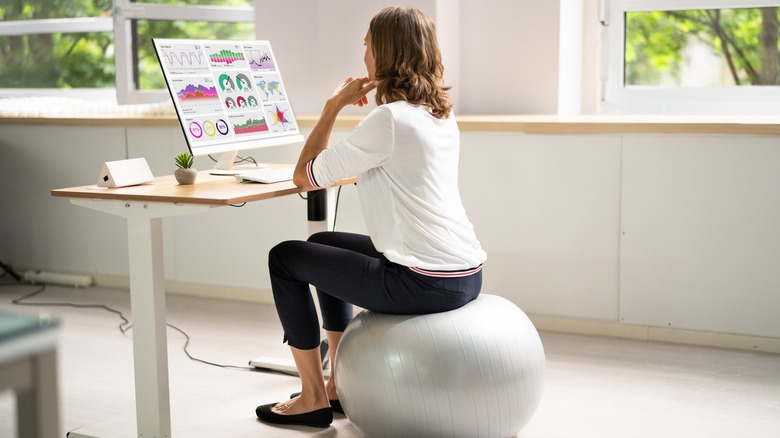 A woman sits on a stability ball at her desk