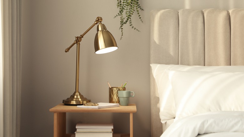 nightstand next to the bed with gold lamp