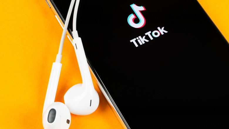 iPhone showing TikTok logo and earbuds
