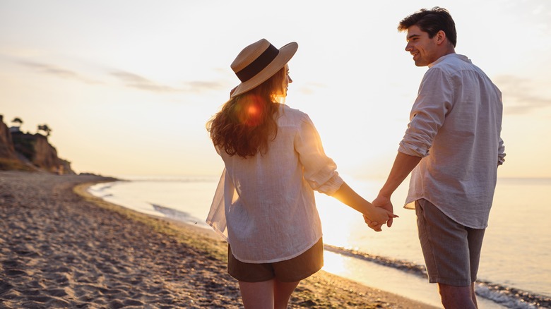 Couple holding hands walking the beach