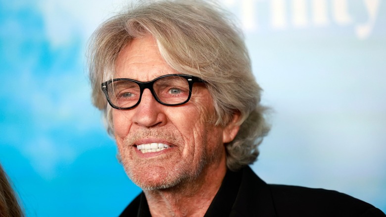 Eric Roberts wearing black glasses and a black blazer.