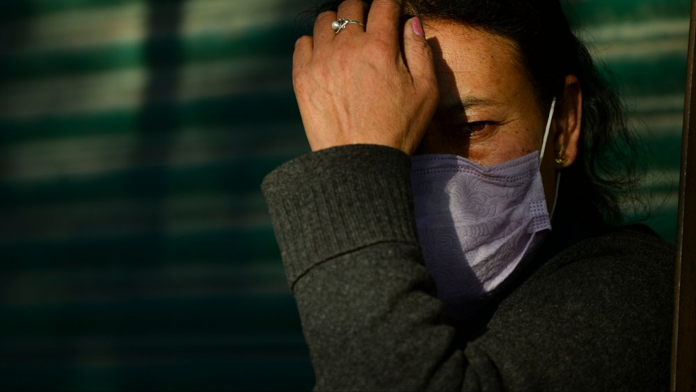 Woman wearing a mask touching his face