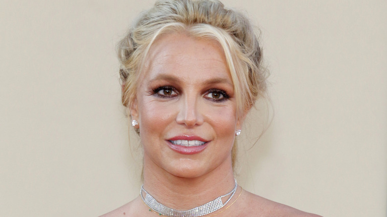 Close up of Britney Spears with hair pulled back wearing diamond earrings and necklace