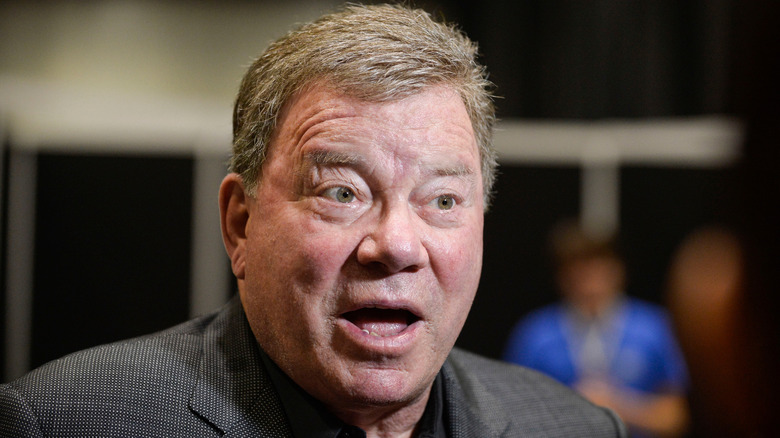 William Shatner speaking with his mouth agape in a grey blazer