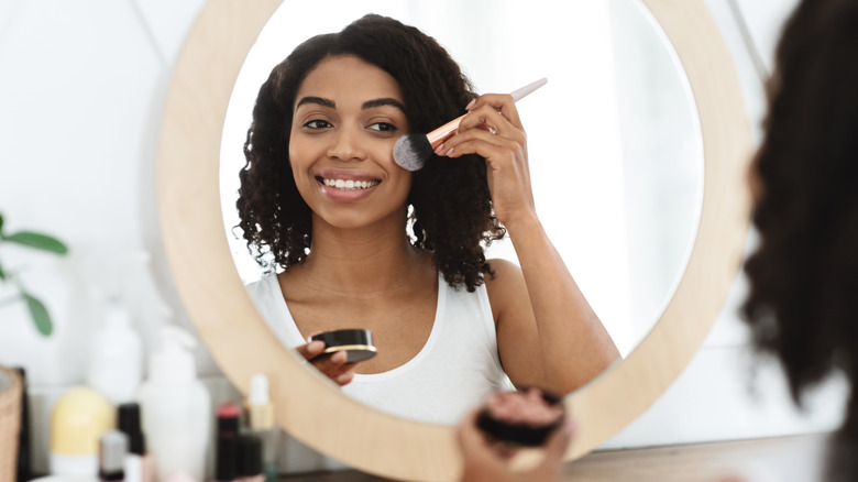 applying blush in mirror