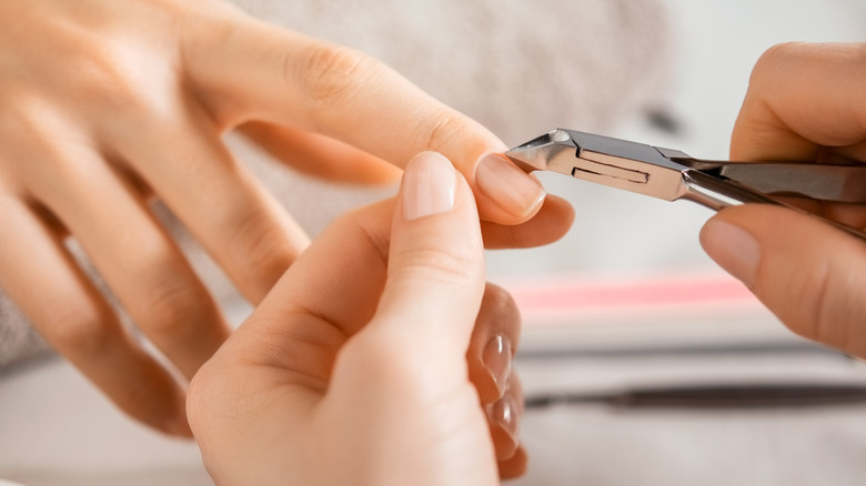 Woman trimming cuticle on nail