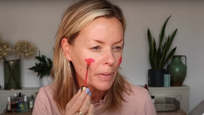 Woman using lipstick as blush 