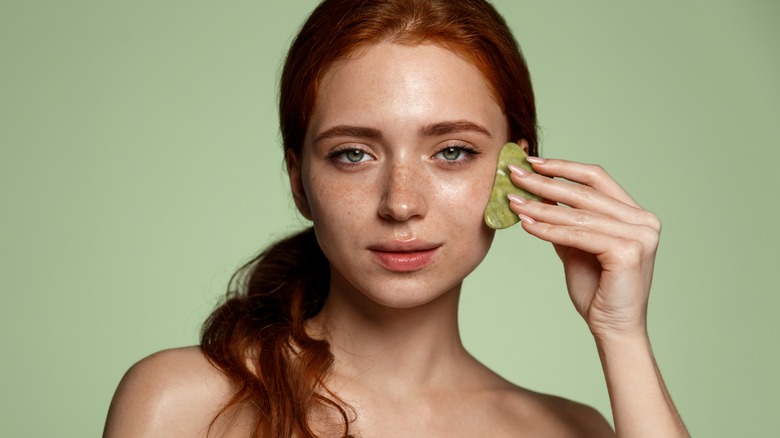 Woman using a gua sha stone on her face