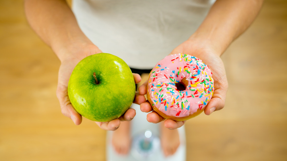 Woman holding apple and donut