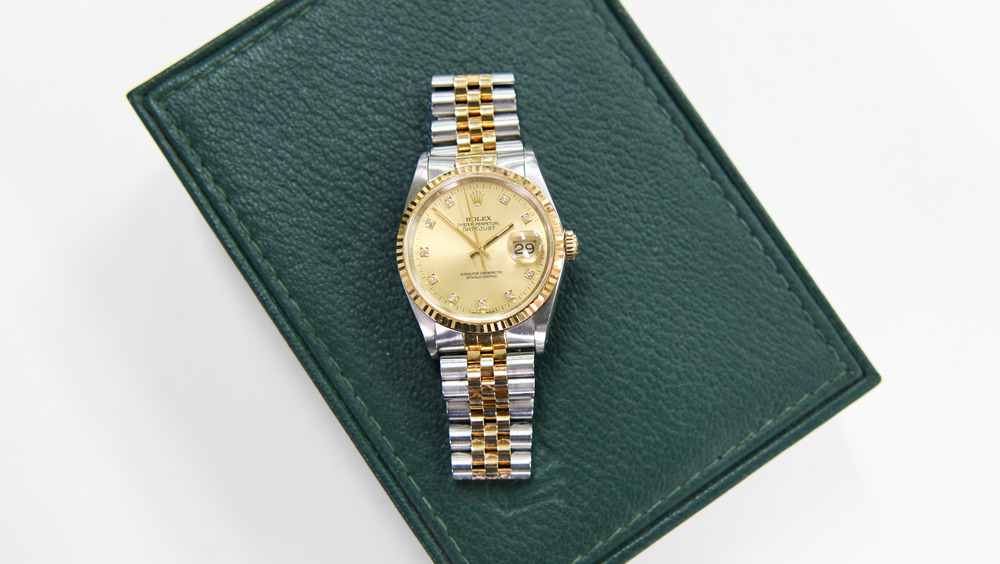 A Rolex watch is placed on top of a green box