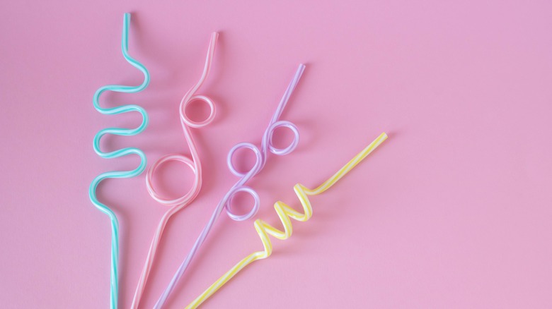 striped plastic straws on pink background