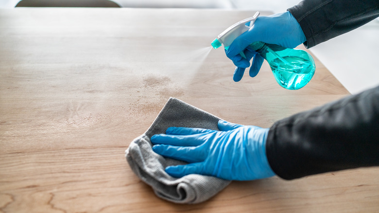 Person spraying cleaner on wood