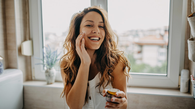 Woman applying moisturizer to face