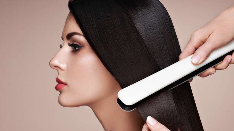 woman using hair straightener 