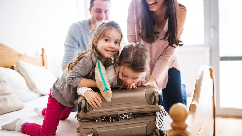 Family trying to close a suitcase