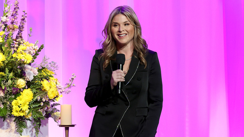 Jenna Bush Hager in a black suit holding a microphone