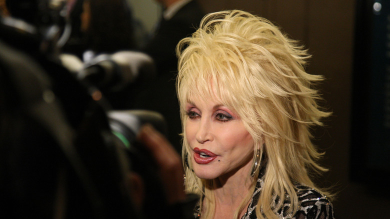 Dolly Parton with layered mullet-style blonde hair and heavy makeup