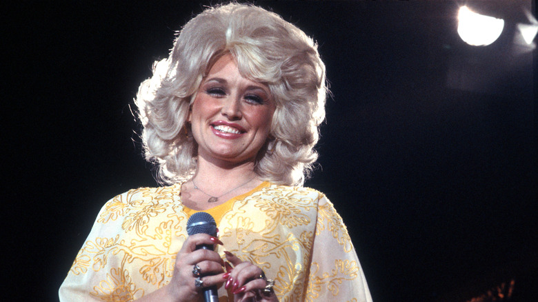Dolly Parton wearing a short blonde wig and yellow dress