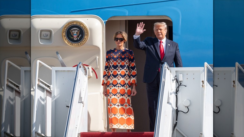 Melania Trump standing with her arms at her side beside Donald Trump.