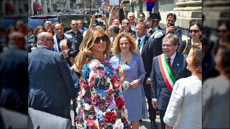 Melania Trump looking over her shoulder in a crowd of people.