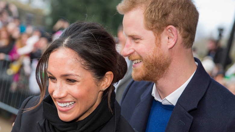 Prince Harry and Meghan Markle smiling in a crowd