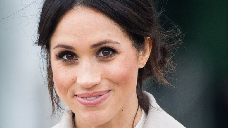 Meghan Markle smiling in a beige coat