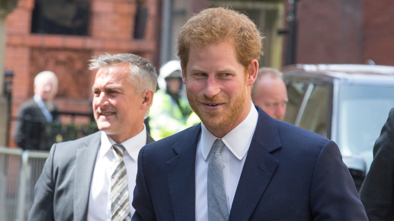 Prince Harry walking outside smiling and looking to the side