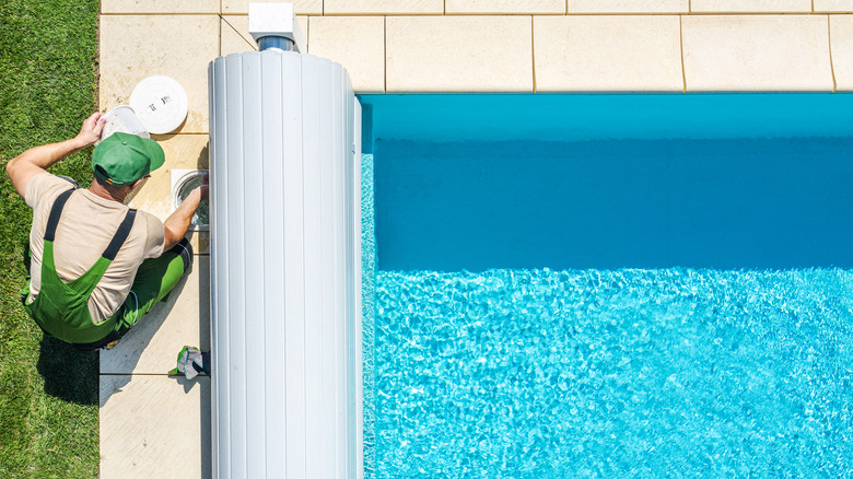 man fixing the filter of a backyard pool