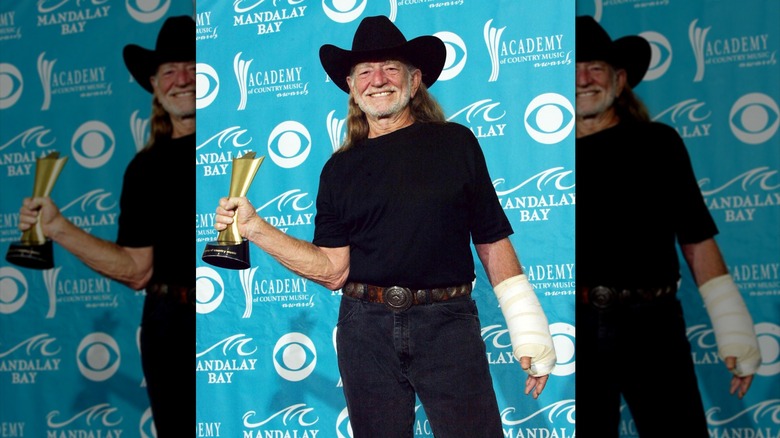 Willie Nelson holding Academy of Country Music award with his hand in a cast