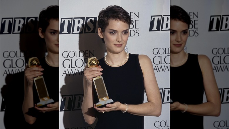 Winona Ryder poses in a black tank top with pearls