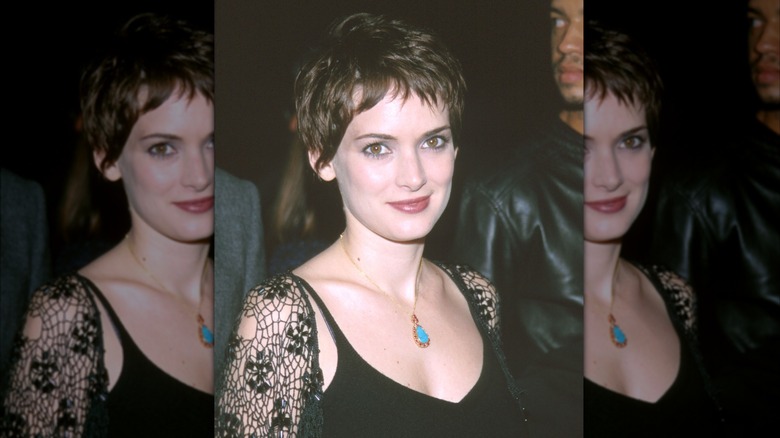Winona Ryder smiles in a black tank top and lacy cardigan