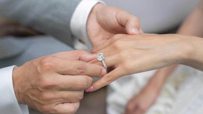 Closeup of engagement ring being slid on finger