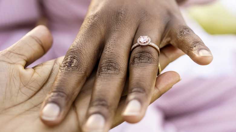 hangs holding with engagement ring