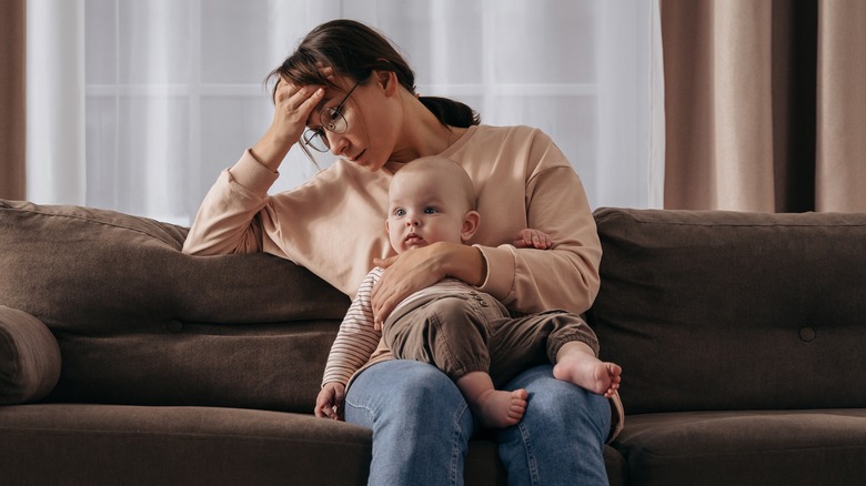 A mother holding a baby looking stressed