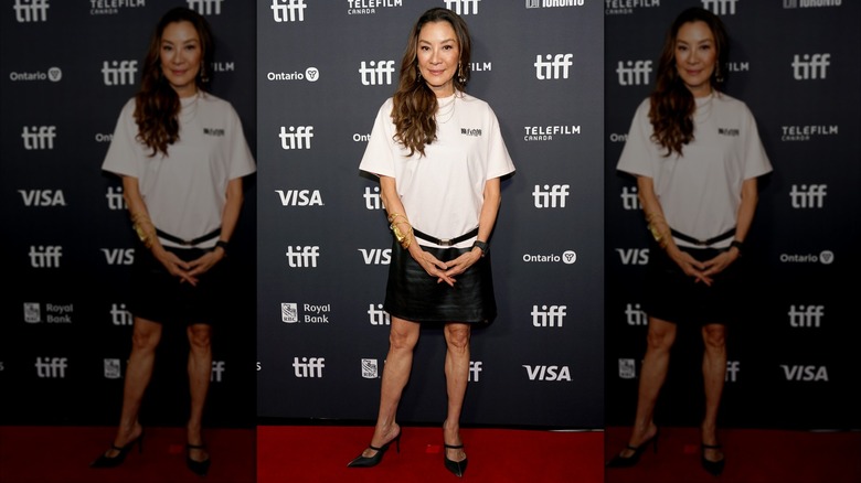 Michelle Yeoh posing on the red carpet in a T-shirt and miniskirt