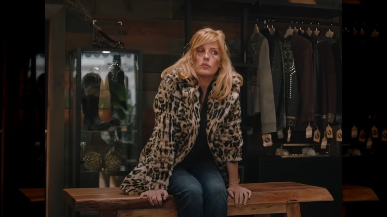 Kelly Reilly as Beth Dutton wearing an animal print coat sitting on a table