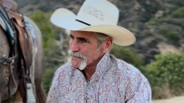 Forrie J Smith kneeling with horse wearing cowboy hat