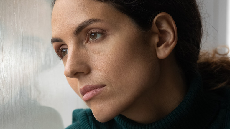 Woman staring out of window, looking pensive
