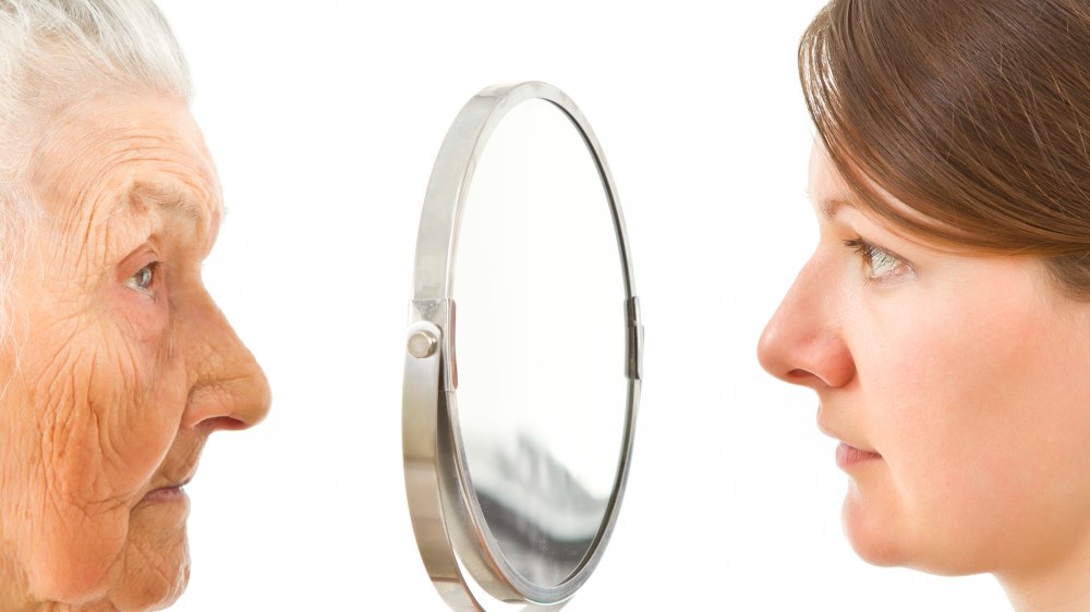 Older woman seeing younger one in mirror